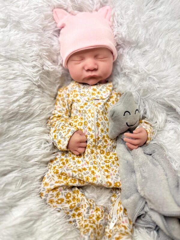 Full body silicone reborn baby boy doll Hudson sleeping in a blue outfit, showcasing the seamless silicone material.