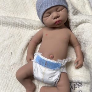 Full body silicone reborn baby boy doll Carter, awake and smiling in a light blue outfit.