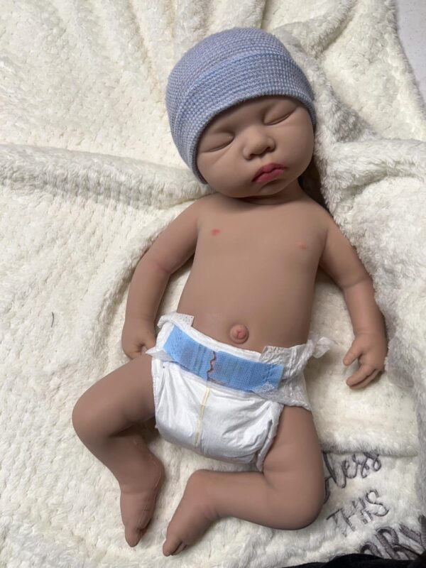 Full body silicone reborn baby boy doll Carter, awake and smiling in a light blue outfit.