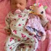 Full silicone reborn baby doll Lucy sleeping soundly in a striped knit outfit.