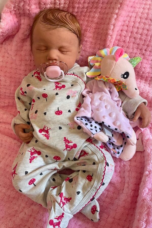 Full silicone reborn baby doll Lucy sleeping soundly in a striped knit outfit.