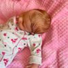 Full silicone reborn baby doll Lucy sleeping soundly in a striped knit outfit.