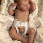 Realistic newborn silicone baby doll Asher posed sitting up, showing his flexible full limbs.