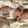 Realistic newborn silicone baby doll Asher posed sitting up, showing his flexible full limbs.