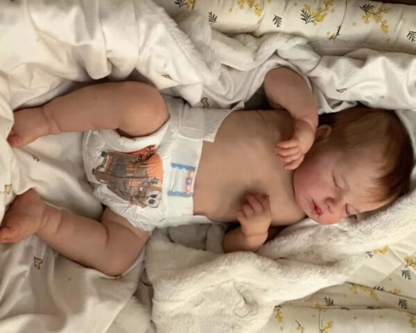 Realistic newborn silicone baby doll Asher posed sitting up, showing his flexible full limbs.