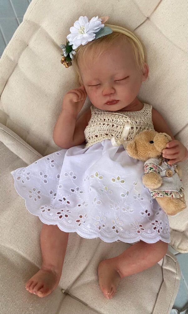 Realistic platinum silicone reborn doll Ella posed in a white blanket.