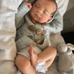 Lifelike reborn baby boy doll Eric with hand-rooted brown hair, dressed in a blue button-up outfit.