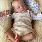 Lifelike vinyl reborn baby boy doll Aiden, dressed in a blue sleeper and sleeping peacefully.