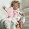 Lifelike vinyl reborn baby girl doll Stella, awake and dressed in a sweet, light-colored outfit.