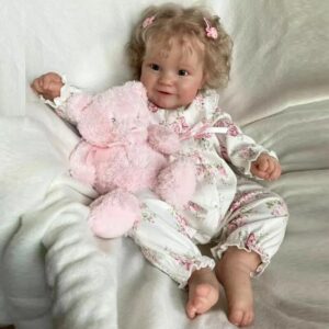 Lifelike vinyl reborn baby girl doll Stella, awake and dressed in a sweet, light-colored outfit.